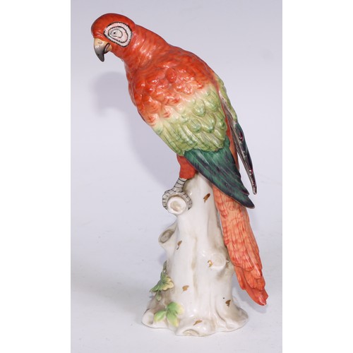 728 - A Continental porcelain model, of a parrot, perched upon an oak tree stump, coloured in tones of gre... 