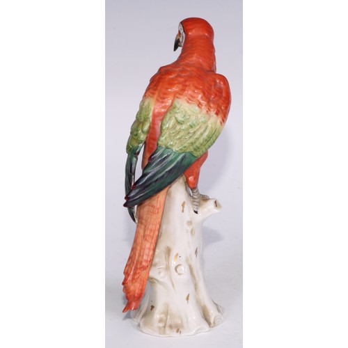 728 - A Continental porcelain model, of a parrot, perched upon an oak tree stump, coloured in tones of gre... 