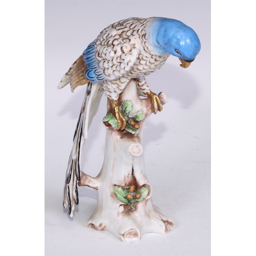 728 - A Continental porcelain model, of a parrot, perched upon an oak tree stump, coloured in tones of gre... 