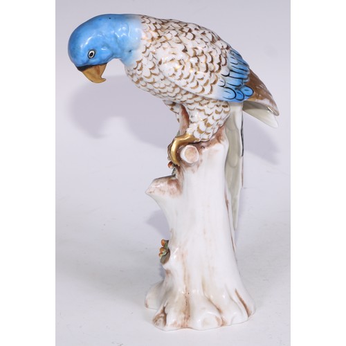 728 - A Continental porcelain model, of a parrot, perched upon an oak tree stump, coloured in tones of gre... 