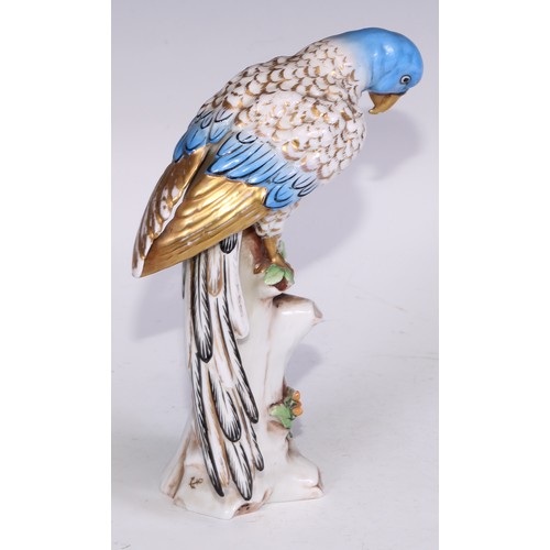 728 - A Continental porcelain model, of a parrot, perched upon an oak tree stump, coloured in tones of gre... 