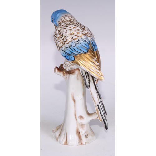 728 - A Continental porcelain model, of a parrot, perched upon an oak tree stump, coloured in tones of gre... 