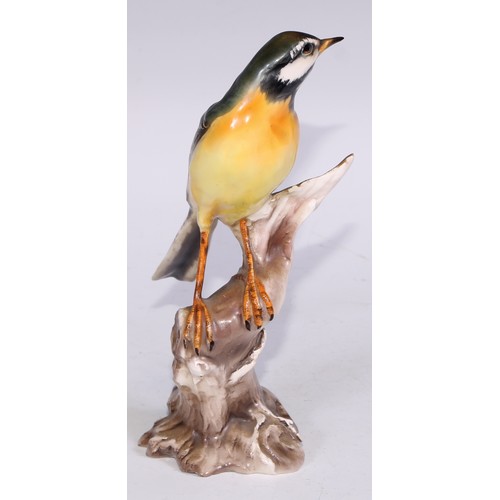 728 - A Continental porcelain model, of a parrot, perched upon an oak tree stump, coloured in tones of gre... 