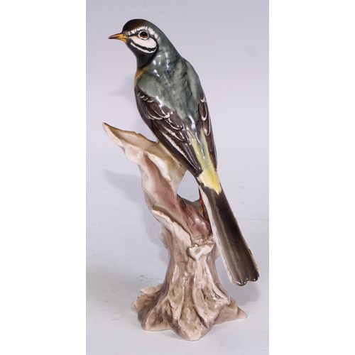 728 - A Continental porcelain model, of a parrot, perched upon an oak tree stump, coloured in tones of gre... 