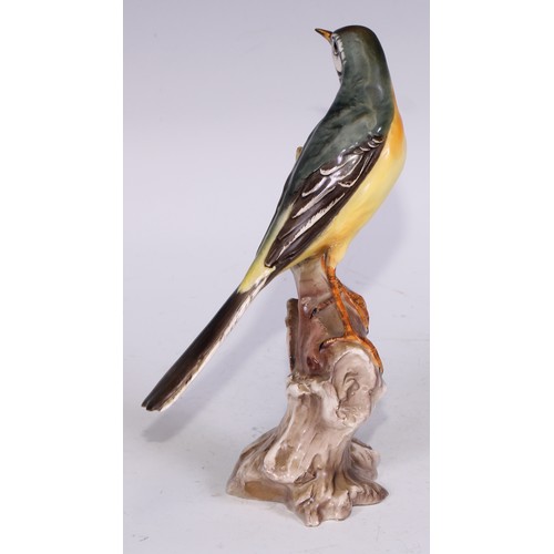 728 - A Continental porcelain model, of a parrot, perched upon an oak tree stump, coloured in tones of gre... 