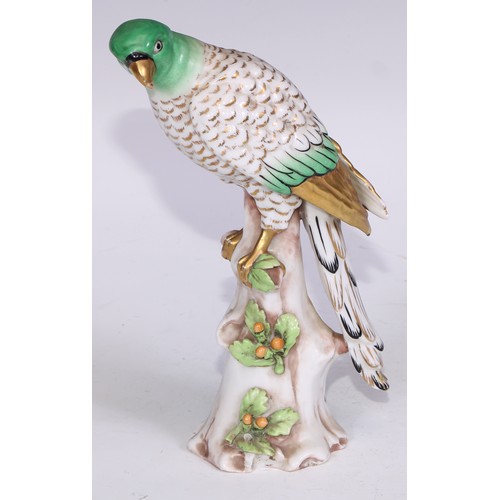 728 - A Continental porcelain model, of a parrot, perched upon an oak tree stump, coloured in tones of gre... 