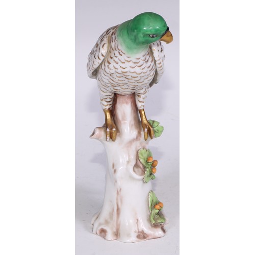 728 - A Continental porcelain model, of a parrot, perched upon an oak tree stump, coloured in tones of gre... 