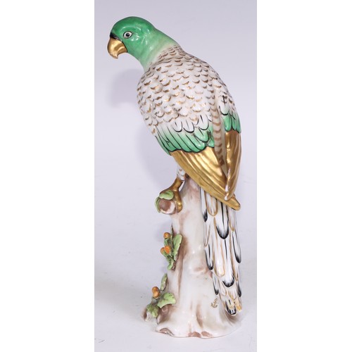 728 - A Continental porcelain model, of a parrot, perched upon an oak tree stump, coloured in tones of gre... 