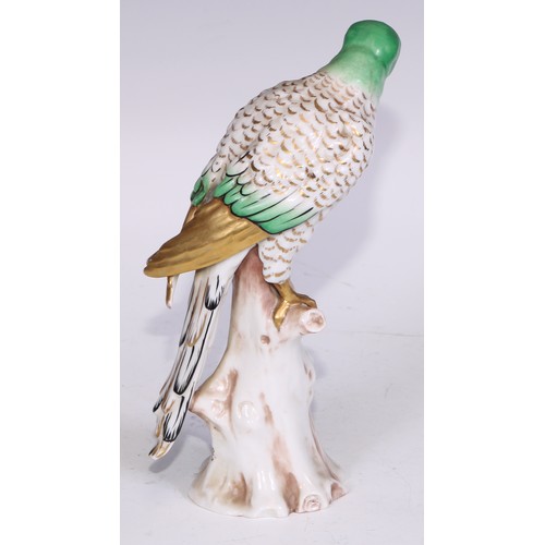 728 - A Continental porcelain model, of a parrot, perched upon an oak tree stump, coloured in tones of gre... 