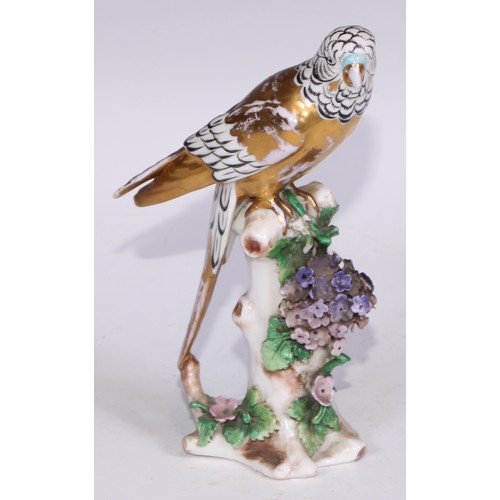 728 - A Continental porcelain model, of a parrot, perched upon an oak tree stump, coloured in tones of gre... 