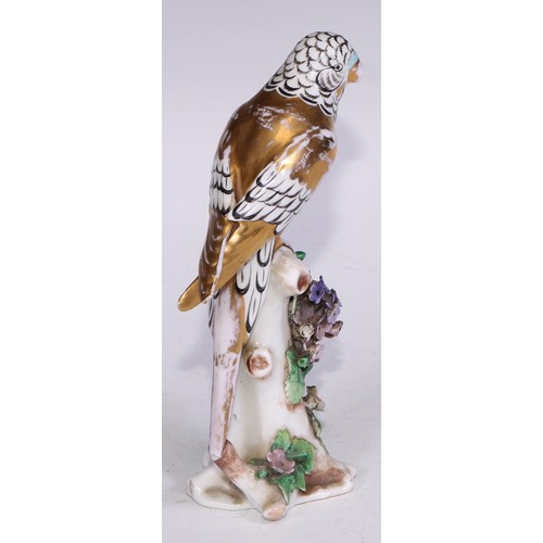 728 - A Continental porcelain model, of a parrot, perched upon an oak tree stump, coloured in tones of gre... 