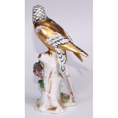 728 - A Continental porcelain model, of a parrot, perched upon an oak tree stump, coloured in tones of gre... 