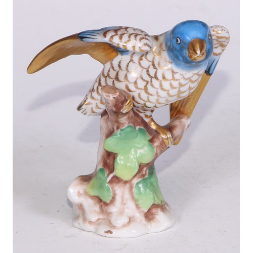 728 - A Continental porcelain model, of a parrot, perched upon an oak tree stump, coloured in tones of gre... 