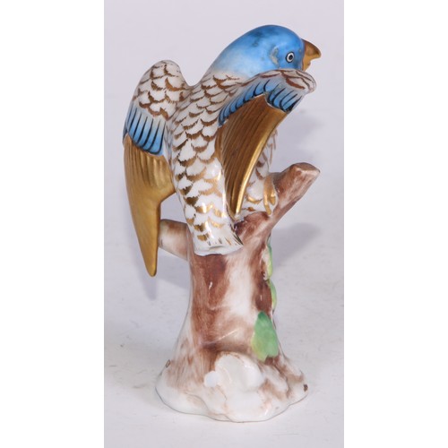 728 - A Continental porcelain model, of a parrot, perched upon an oak tree stump, coloured in tones of gre... 