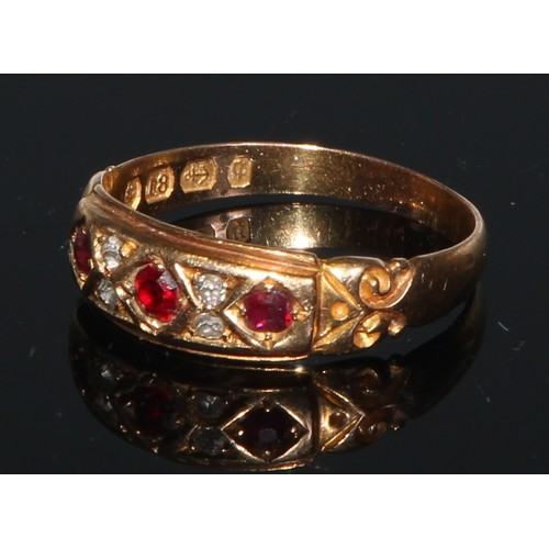 244 - An 18ct gold ring, set with three rubies divided by four small diamonds, engraved with scrolls to sh... 