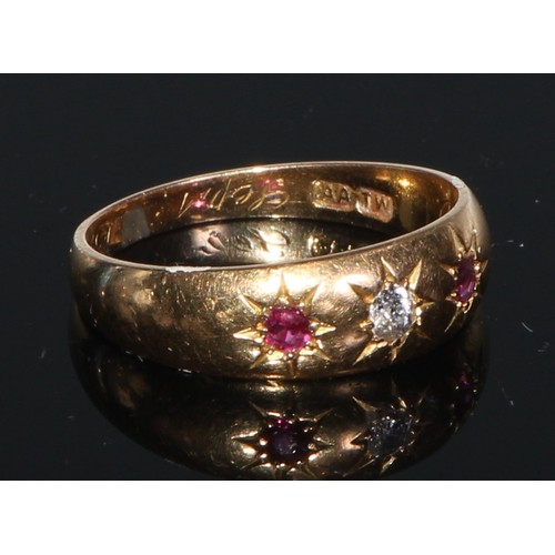 244 - An 18ct gold ring, set with three rubies divided by four small diamonds, engraved with scrolls to sh... 