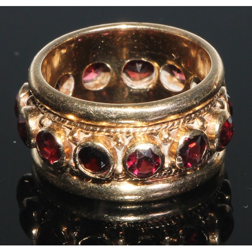 108 - A 14ct gold eternity ring, set with a band of colette set facet cut garnets, within ripe twist and r... 