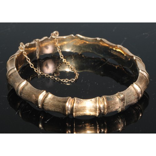 148 - A 9ct gold hinged bangle hollow cast with 'linked bones', 7.25cm in diameter, 12.1g