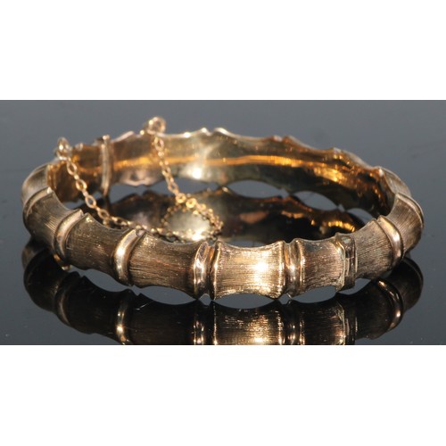 148 - A 9ct gold hinged bangle hollow cast with 'linked bones', 7.25cm in diameter, 12.1g