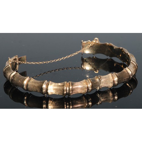 148 - A 9ct gold hinged bangle hollow cast with 'linked bones', 7.25cm in diameter, 12.1g