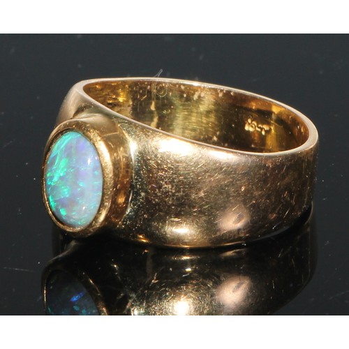 240 - An 18ct gold and opal ring, the central oval cabochon stone with play of colour in blue and green, c... 