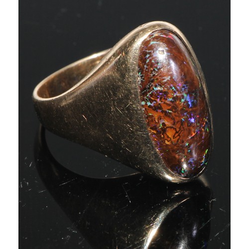 154 - A black opal and 9ct gold ring, the large elongated oval cabochon stone set within within a plain sh... 