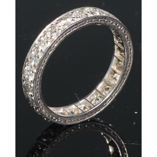 166 - A diamond and white metal eternity ring, a continuous band of brilliant cut stones, engraved with a ... 