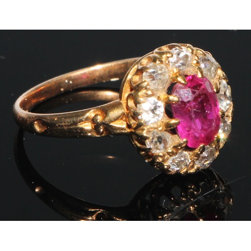 162 - A diamond and ruby cluster ring, the central oval facet cut ruby set within within nine brilliant cu... 