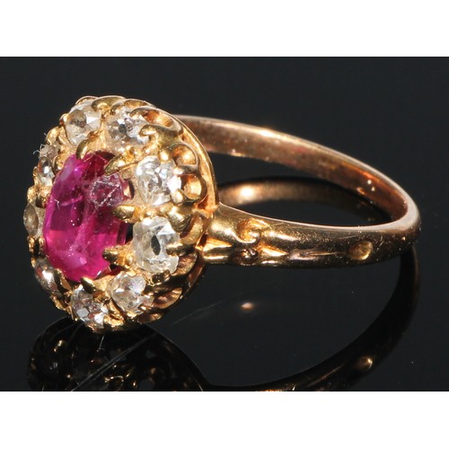 162 - A diamond and ruby cluster ring, the central oval facet cut ruby set within within nine brilliant cu... 