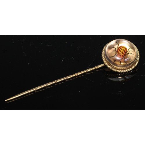 134 - A 19th century yellow metal stick/scarf pin, the essex crystal cabochon head reverse painted with a ... 