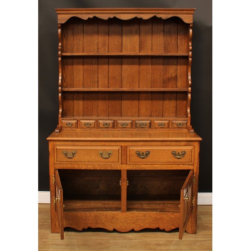 112 - An oak dresser, moulded cornice above a pair of plate racks and seven small drawers, the projecting ... 