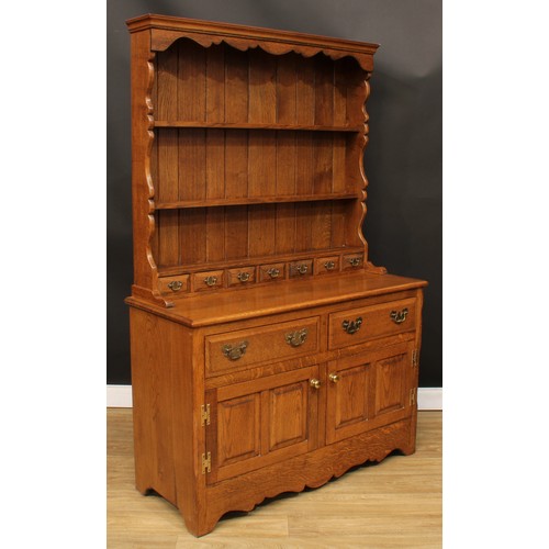 112 - An oak dresser, moulded cornice above a pair of plate racks and seven small drawers, the projecting ... 