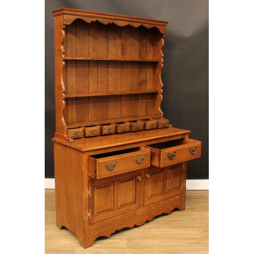 112 - An oak dresser, moulded cornice above a pair of plate racks and seven small drawers, the projecting ... 