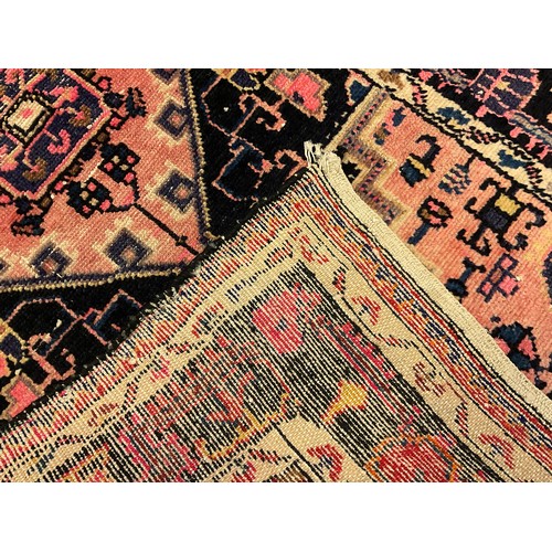 86 - A Persian/Turkish rug, central geometric panel within stepped surround, in tones of pink, black, blu... 