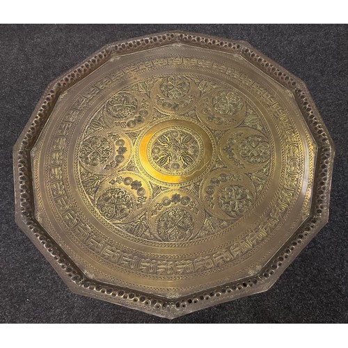 135 - A Benares dodecagonal brass top table, embossed decoration, folding base, 56cm high;  72cm diameter;... 