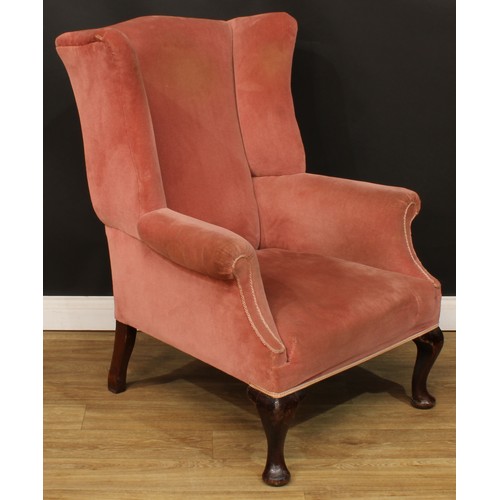 215 - A George II Revival wingback armchair, stuffed-over upholstery, scroll arms, cabriole forelegs, pad ... 