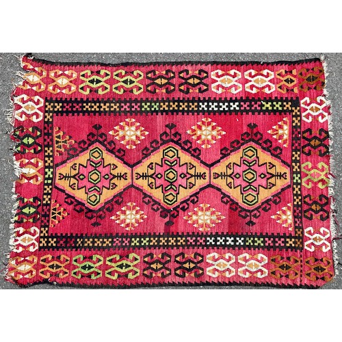 467 - A Turkish woollen rug, with geometrical motifs on a red ground, 150cm x 105cm