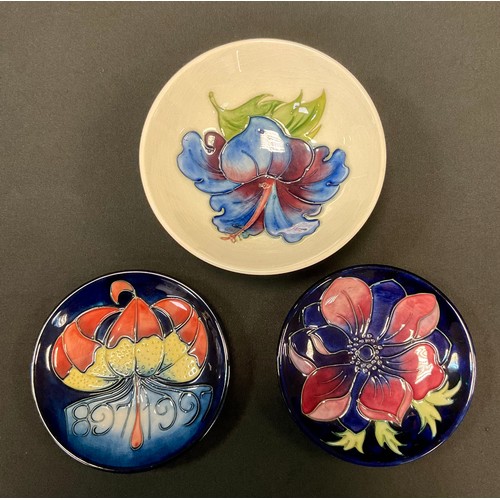 49 - A Moorcroft Hibiscus pattern dish, tube lined with blue flowerhead on an ivory ground, 14cm diam, im... 