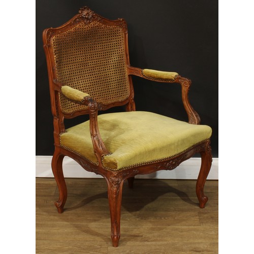 106 - A Louis XV design fauteuil or open armchair, shaped cresting carved with trailing flowering stems an... 