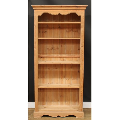 595 - A pine open bookcase, moulded cornice above four adjustable shelves, flanked by fluted stiles, plint... 