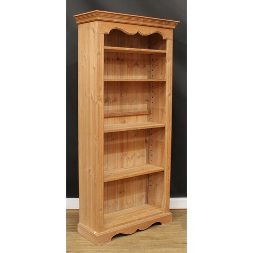 595 - A pine open bookcase, moulded cornice above four adjustable shelves, flanked by fluted stiles, plint... 