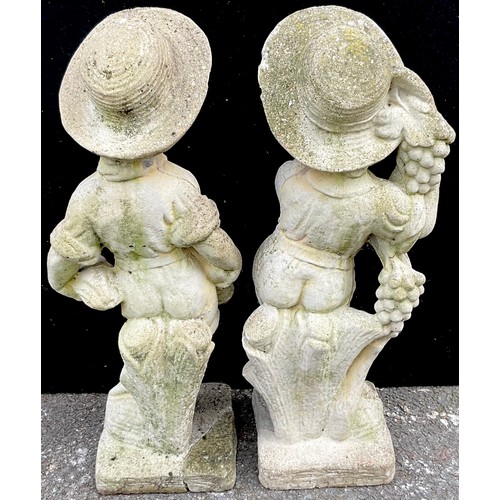 3059 - A pair of reconstituted garden statues, of young boys, one holding grapes,  the other a scythe, 69cm... 