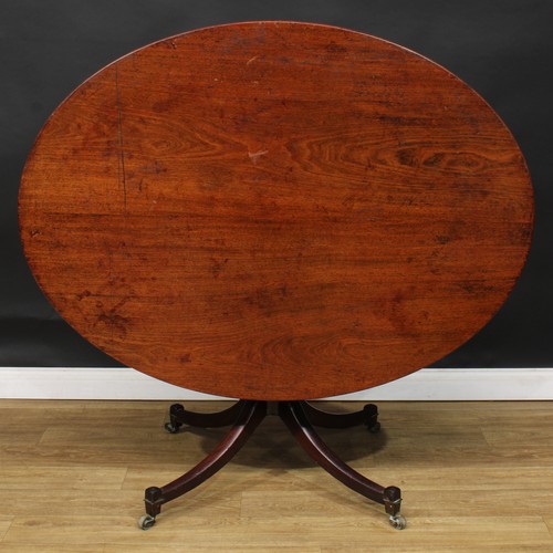 1761 - A Regency mahogany centre table, oval tilting top, turned column, sabre legs, brass casters, 71cm hi... 