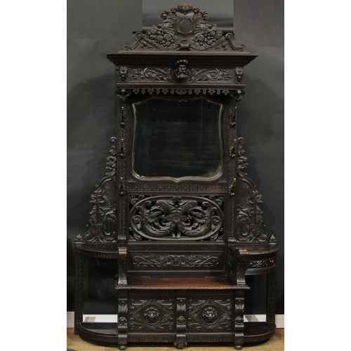 1656 - A late 19th century oak country house entrance hall stand, shaped pediment above a bevelled mirror p... 