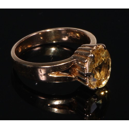 413 - A 18ct gold ring, set with a single oval cut yellow sapphire, size J/K, the stone 10mm high, the pla... 