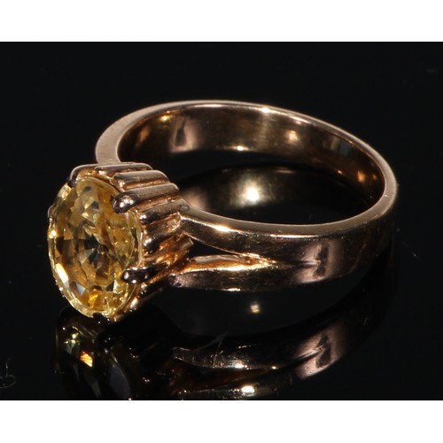 413 - A 18ct gold ring, set with a single oval cut yellow sapphire, size J/K, the stone 10mm high, the pla... 