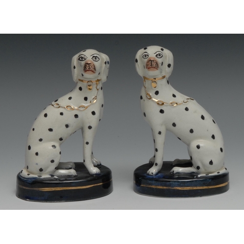 678 - A pair of Staffordshire dalmations, seated to the the left and right, blue oval bases, 13cm high, c.... 