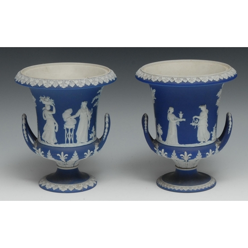 556 - A pair of early 20th century Wedgwood Jasperware two handled campana shaped vases, typically sprigge... 