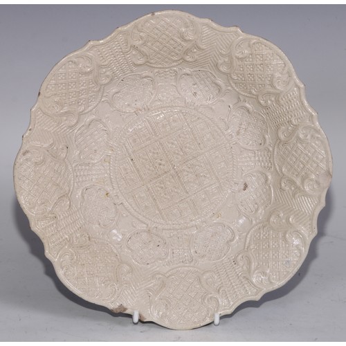 534 - An 18th century salt glazed stoneware shaped circular plate, moulded in the Rococo taste with leafy ... 