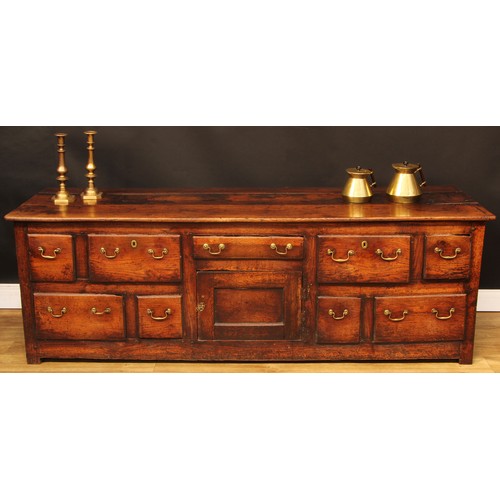 1614 - A George III vernacular oak low dresser, plank rectangular top above an arrangement of drawers and a... 